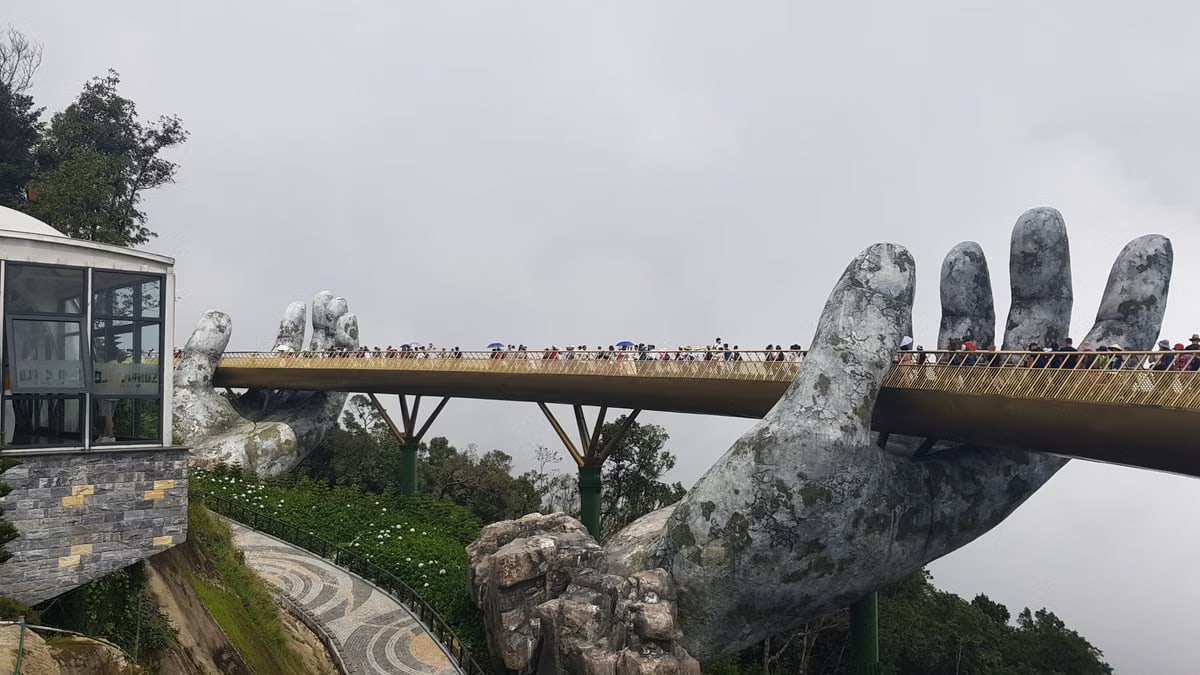Golden Bridge held by giant hands in Ba Na Hills, Vietnam, attracts tourists.